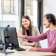 Zwei Personen arbeiten gemeinsam am Computer im Büro.